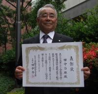 （表彰状を手に笑顔の田中会長）